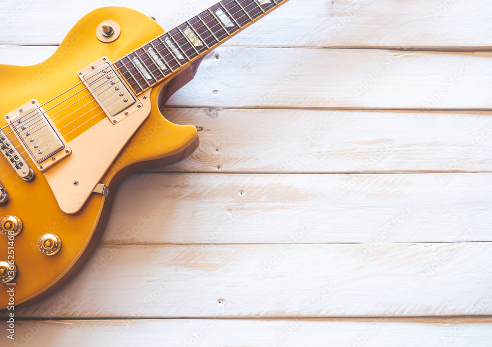 Obraz premium Beautiful classic golden electric guitar on a white wooden table, with copy space