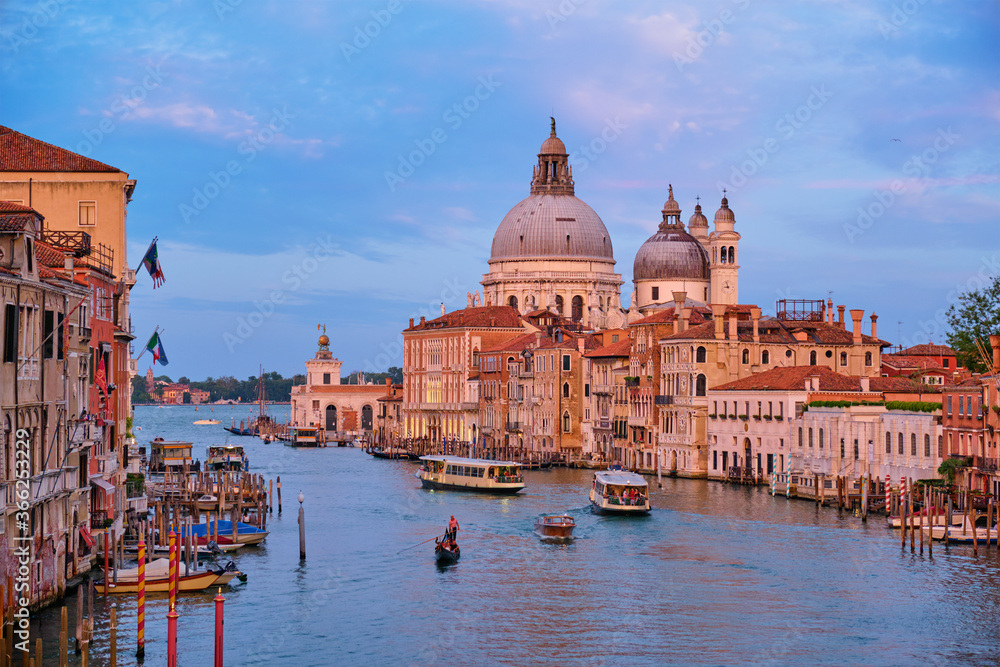 Panorama of Venice Grand Canal with gondola boats and Santa Maria della Salute church on sunset from Ponte dell'Accademia bridge. Venice, Italy