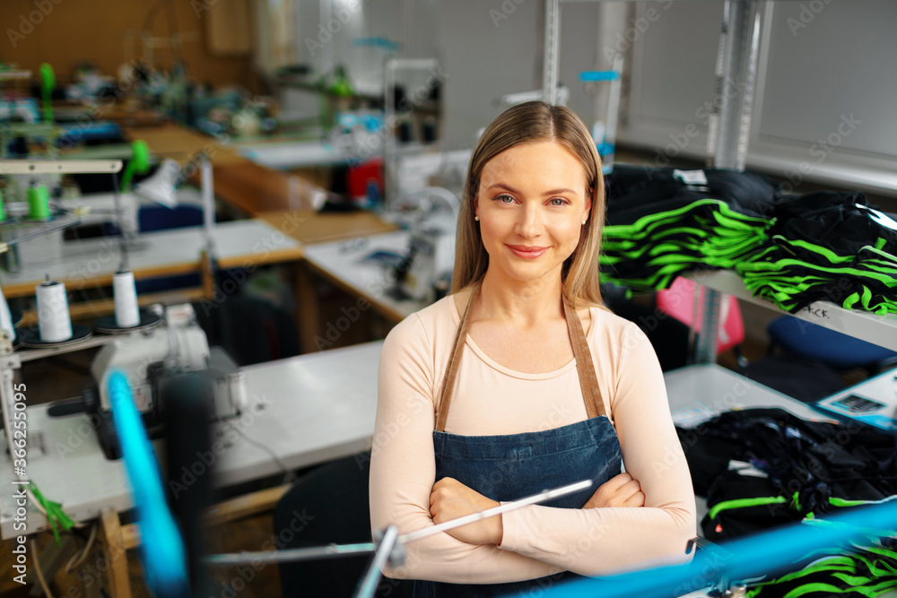 Portrait of a seamstress standing at working place and looking at camera Portrait of a seamstress standing at working place and looking at camera