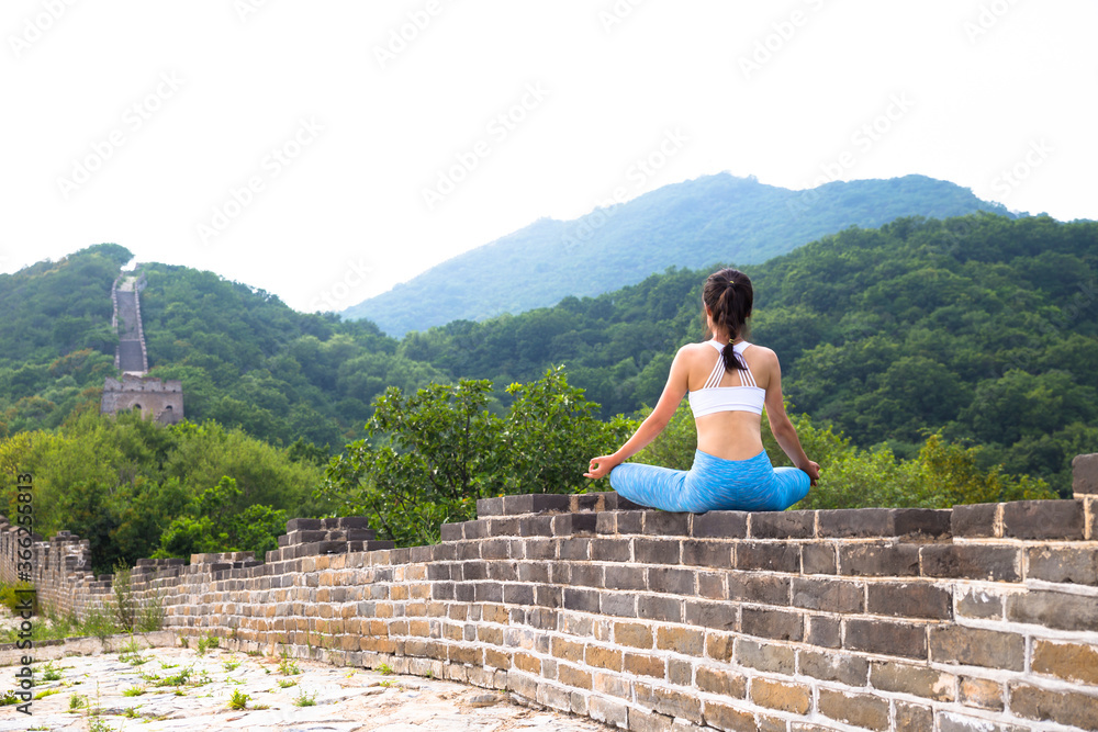 Asian girl sit in meditation on the Great Wall in Beijing