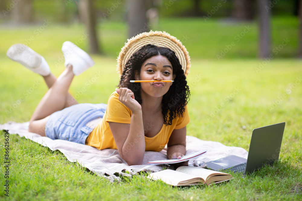 Pretty black girl being silly and making faces during studies with laptop at park Pretty black girl being silly and making faces during studies with laptop at park
