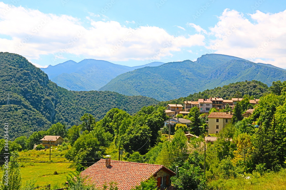 fondo paisaje con panorámica de un pequeño pueblo entre valles y montañas en verano