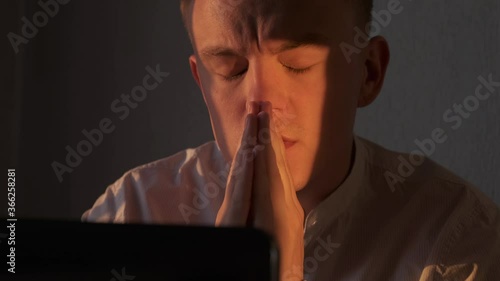 Businessman praying at office looking at laptop screen