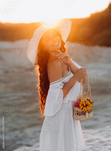 Magnificentl girl in a white hat posing at sunset photo