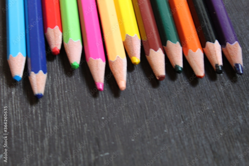 Many colored pencils on a black background. New pencils. Isolated background to insert text, selective focus Many colored pencils on a black background. New pencils. Isolated background to insert text, selective focus