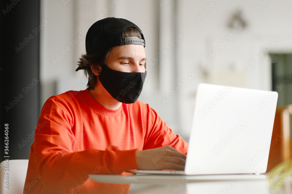 The man sits alone at a table in the open space, drinking coffee and working on his laptop. Freelance concept The man sits alone at a table in the open space, drinking coffee and working on his laptop. Freelance concept