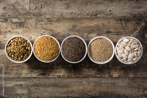 Assortment of different seeds in bowls on wooden table. Top view
