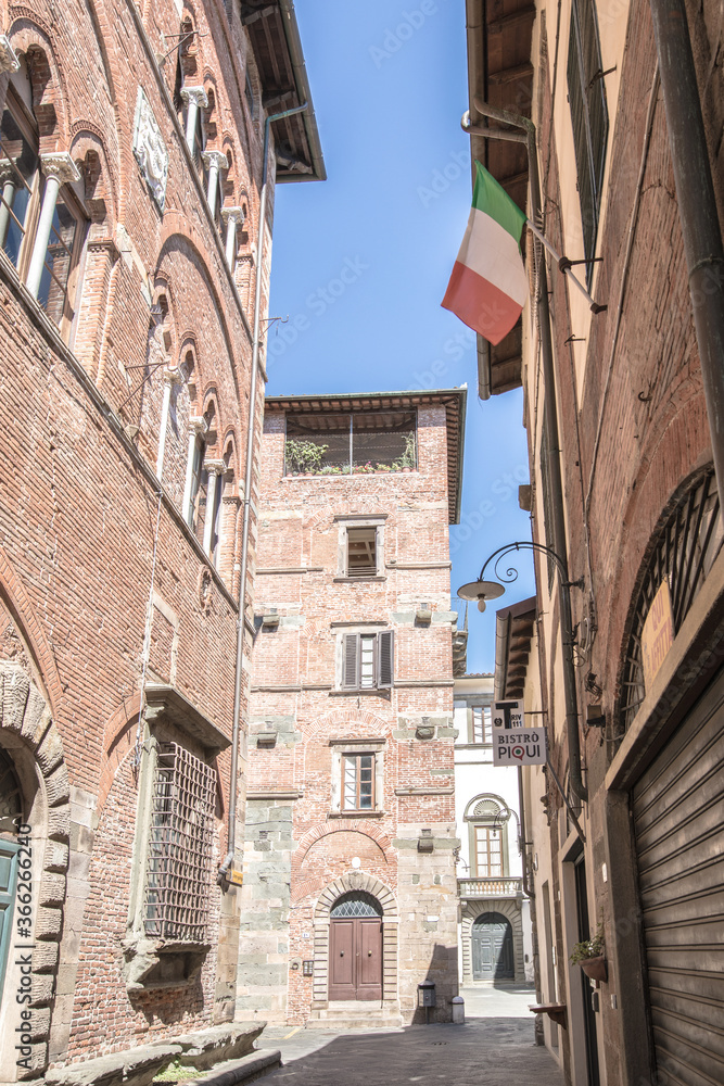 Street of Lucca in Italay, Tuscany. Hot summer day in an italian city with architecture and italian flag.