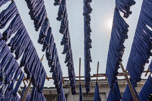 Fotografi Blue dyed silk hanging in fabric weaving factory in Amarapura, Myanmar