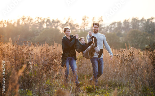 Beautiful young family with small son on a walk in autumn nature.