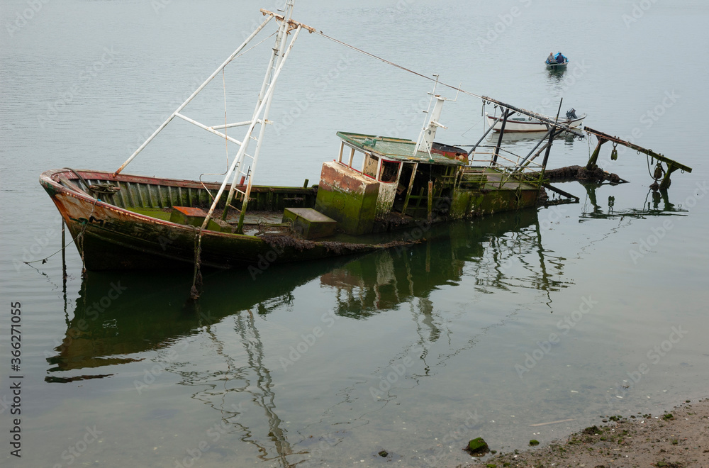 An abandoned fisher boat reflex during morning, in Douro River, Oporto, Portugal.