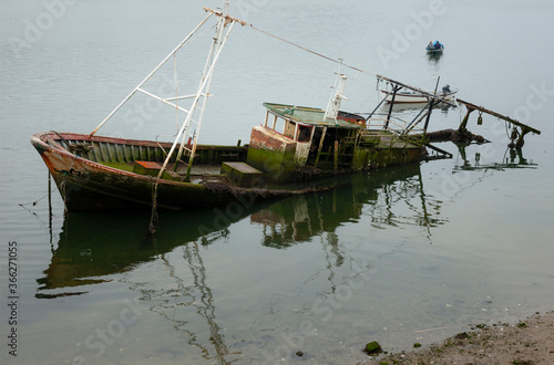 An abandoned fisher boat reflex during morning, in Douro River, Oporto, Portugal.