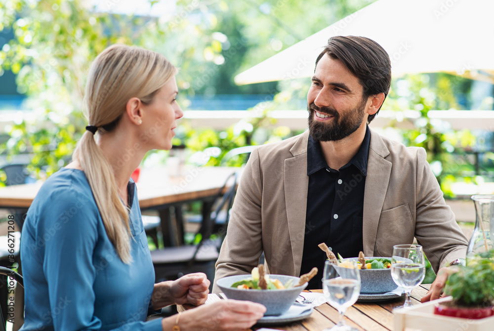 Happy couple sitting outdoors on terrace restaurant, talking. Happy couple sitting outdoors on terrace restaurant, talking.