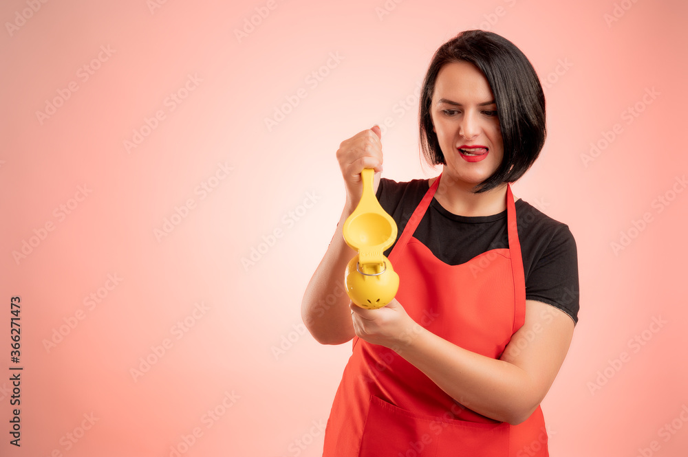 Woman employed at supermarket with red apron and black t-shirt squeeze a lemon Woman employed at supermarket with red apron and black t-shirt squeeze a lemon