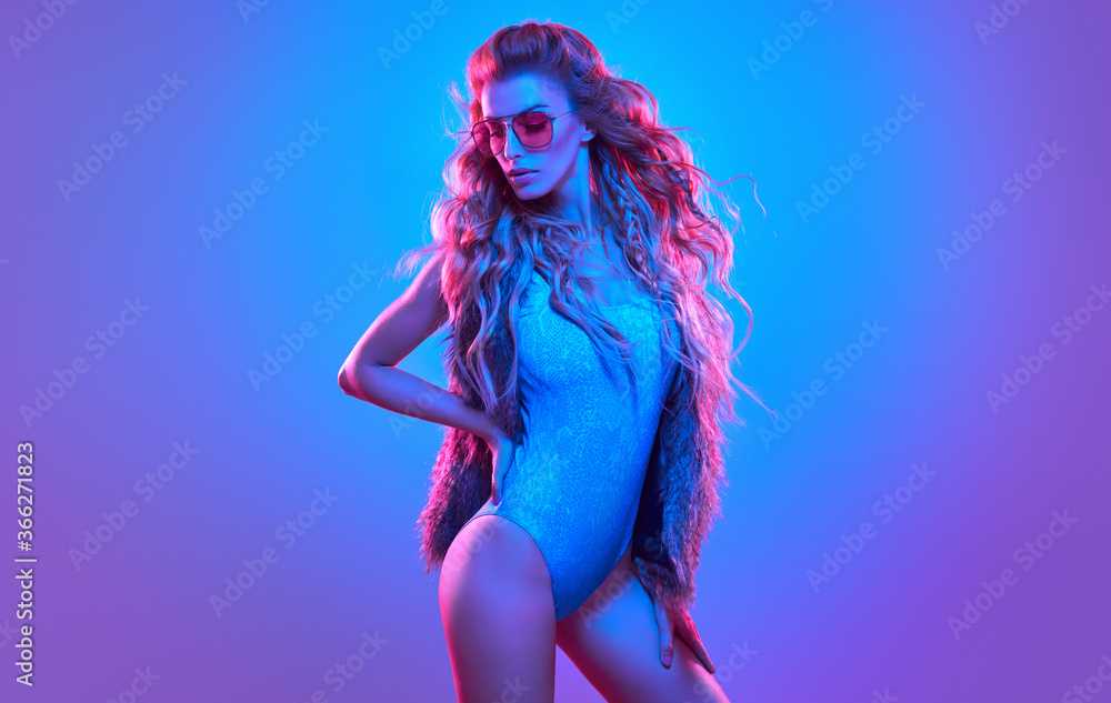 Fototapeta Fashion. Woman in Colorful neon light. Sexy girl in disco bodysuit, makeup. Party disco neon nightclub vibes. Fashionable model portrait, creative art neon pink blue light
