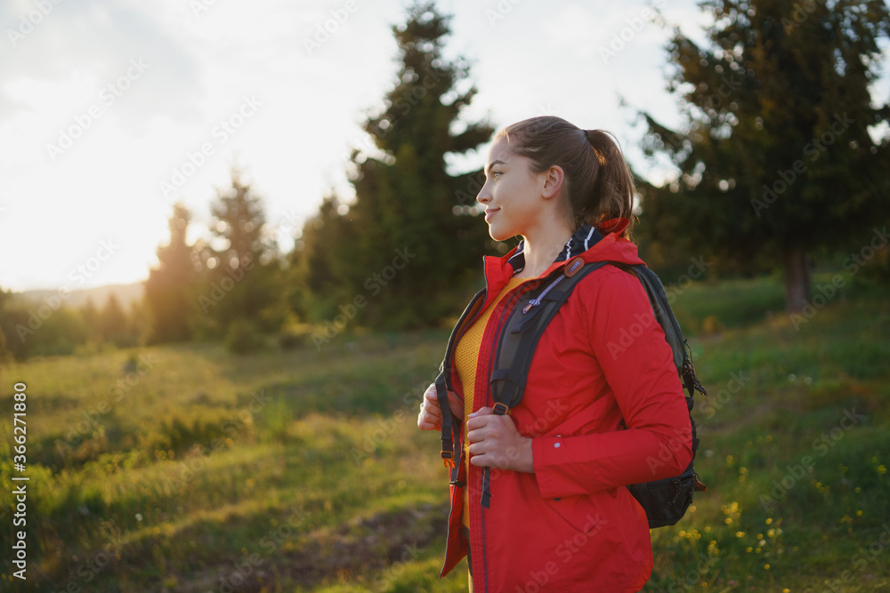 Young woman on a walk outdoors on meadow in summer nature, walking.