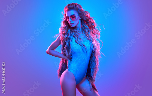 Fashion. Woman in Colorful neon light. Sexy girl in disco bodysuit  makeup. Party disco neon nightclub vibes. Fashionable model portrait  creative art neon pink blue light