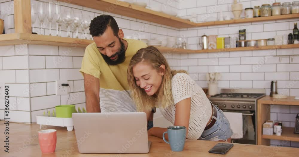 Happy couple smiling while using laptop at home Happy couple smiling while using laptop at home