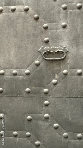 Vertical photo of metallic grey door elements. Dark forged iron material, specific grain on metal surface