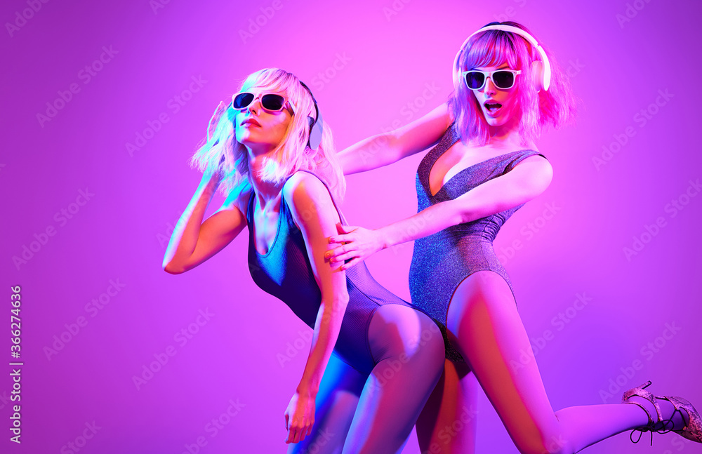 Fashion. Two DJ girl in Colorful neon light enjoy music, friends ...