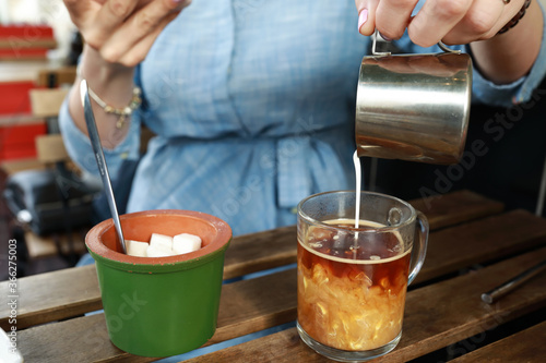 Woman pouring cream into coffee mug