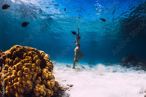 Woman dive underwater with yellow fins in tropical ocean.