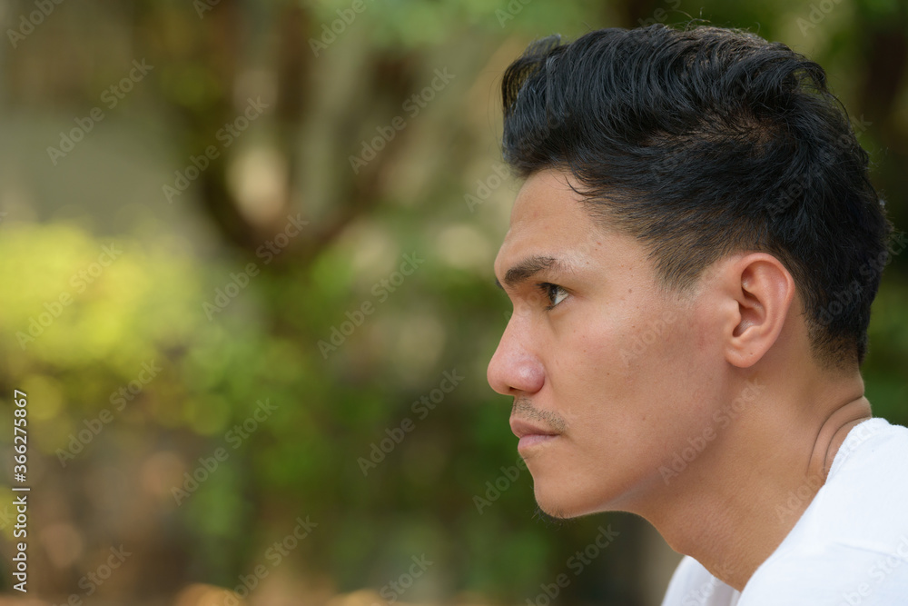 Closeup profile view of handsome Asian man outdoors Closeup profile view of handsome Asian man outdoors