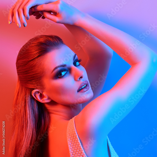 High Fashion. Woman in colorful neon light, make-up. Sexy girl, stylish hair, trendy makeup. Party disco neon style. Creative art beauty portrait, fashionable model face, bright make up
