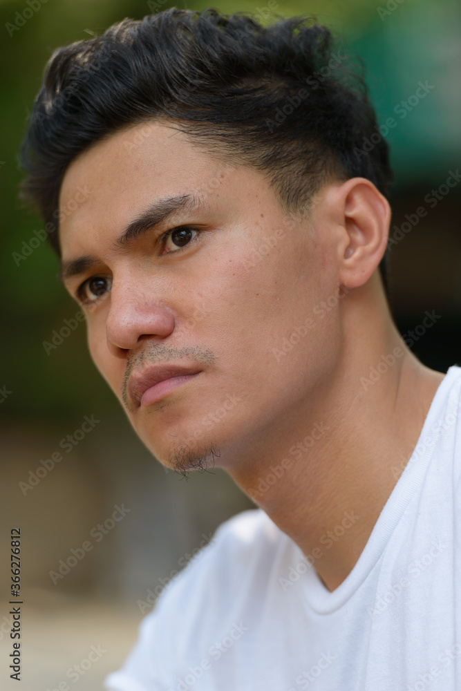 Face of handsome Asian man thinking outdoors Face of handsome Asian man thinking outdoors