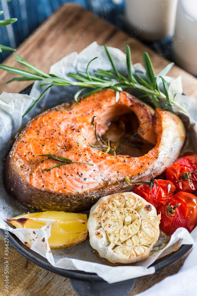 baked salmon steak with rosemary, lemon and spices in a black pan on a blue rustic background. Balanced diet baked salmon steak with rosemary, lemon and spices in a black pan on a blue rustic background. Balanced diet