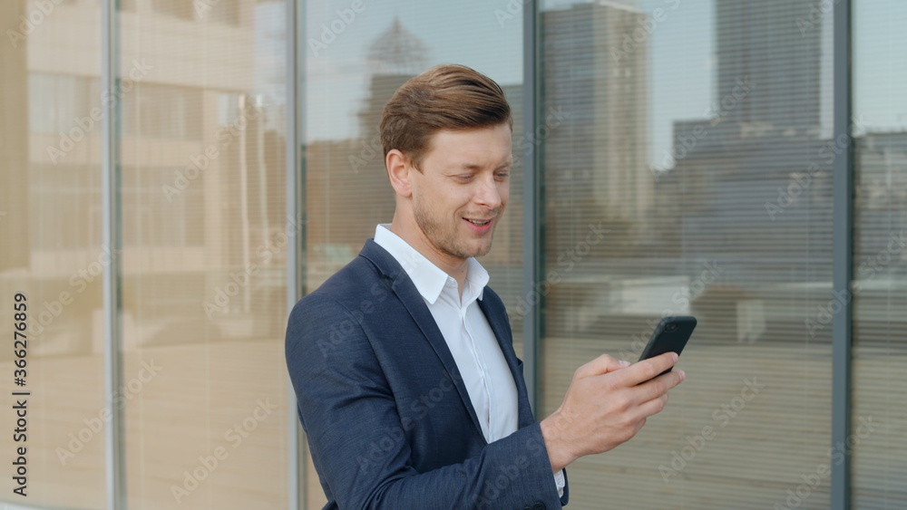 Surprised businessman receiving good news on smartphone at street Surprised businessman receiving good news on smartphone at street