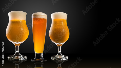 Different glasses and cups with beer, on a dark table, dark background and copy space