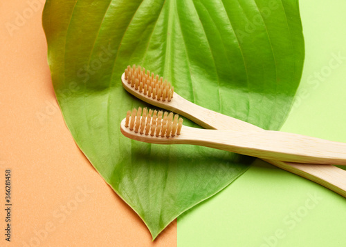 two wooden toothbrushes on a green orange background  plastic rejection concept