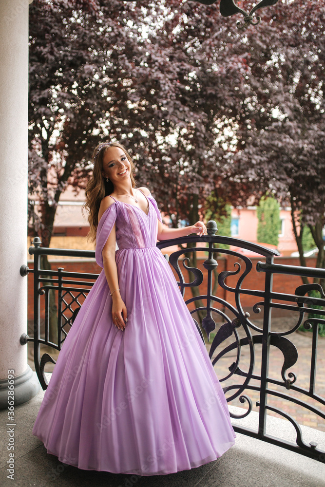 Fototapeta premium Woman in evening dress stand on terrace and smile. Beautiful hairsyle