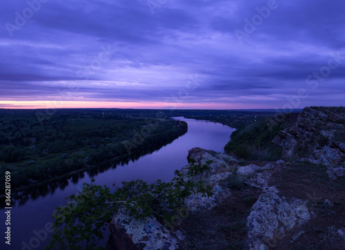 .Purple sunset over the river. View from the mountain to the river and forest