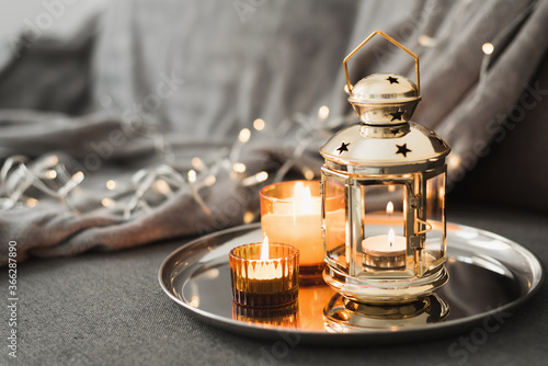 Golden lantern and burning candles on a metal tray. Traditional decor for muslim holidays. Eid Al Adha celebration. Ramadan
