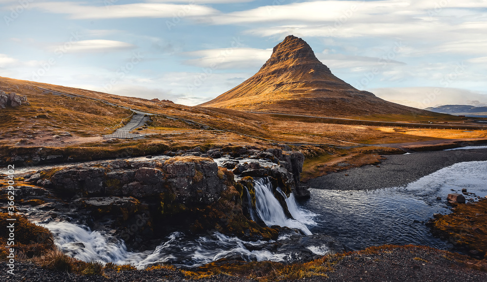 Amazing mountain landscape with pefect sky of Iceland. Impressive view on famous Kirkjufell mountain and Kirkjufellsfoss waterfall at sunny day. Iconic location for landscape photographers.