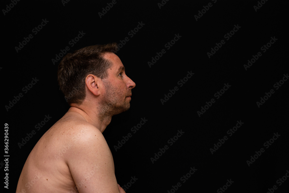 Side view thoughtful undressed middle man demonstrating reverie. Black wall Side view thoughtful undressed middle man demonstrating reverie. Black wall