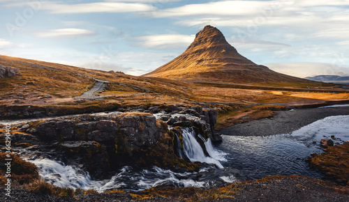 Amazing mountain landscape with pefect sky of Iceland. Impressive view on famous Kirkjufell mountain and Kirkjufellsfoss waterfall at sunny day. Iconic location for landscape photographers.