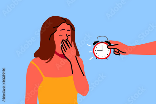 Health, care, dream, relaxation concept. tired young woman yawning with closed eyes exhausted after long hard day and invisible person holding alarm clock showing late time. Time sleep or wake up.