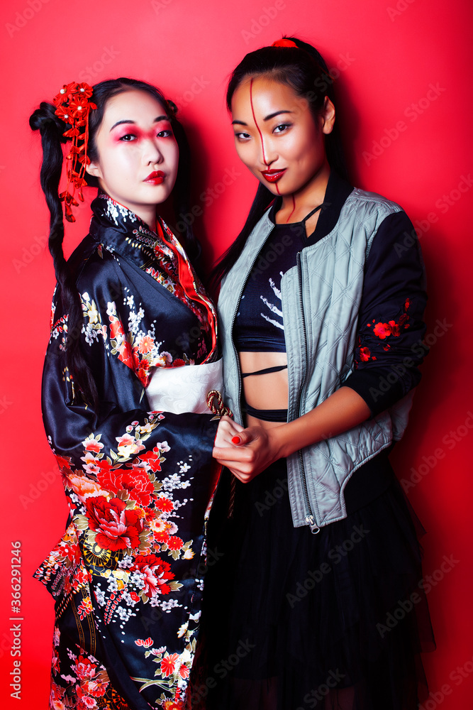 two pretty geisha girls friends: modern asian woman and traditional wearing kimono posing cheerful on red background two pretty geisha girls friends: modern asian woman and traditional wearing kimono posing cheerful on red background