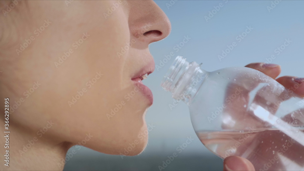 Woman drinking water after yoga training outdoors. Girl resting after workout Woman drinking water after yoga training outdoors. Girl resting after workout