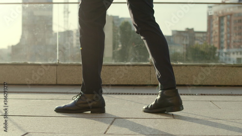 Anonymous business man legs dancing at street. Businessman stepping on sidewalk