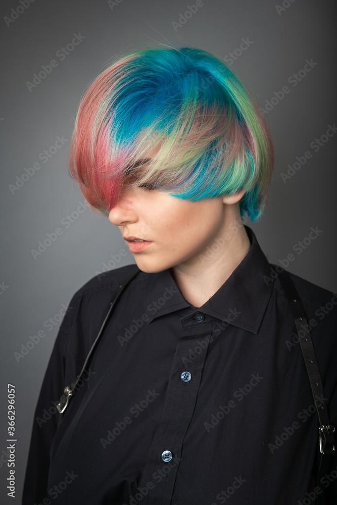 Portrait of a young woman with multi colored hair against a grey background