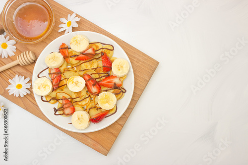 Trendy food - pancake cereal. Heap of mini cereal pancakes on a white plate  copy space. Strawberries  bananas  and honey. A beautiful and healthy Breakfast. Top view.