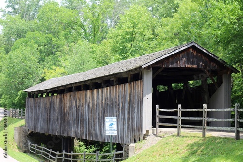 The wood covered bridge in the country on a sunny day.