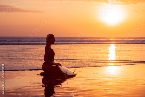 Portrait of surfer girl with beautiful body on the beach with surfboard at colourful sunset time