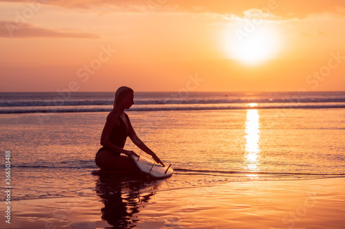 Portrait of surfer girl with beautiful body on the beach with surfboard at colourful sunset time © Lila Koan