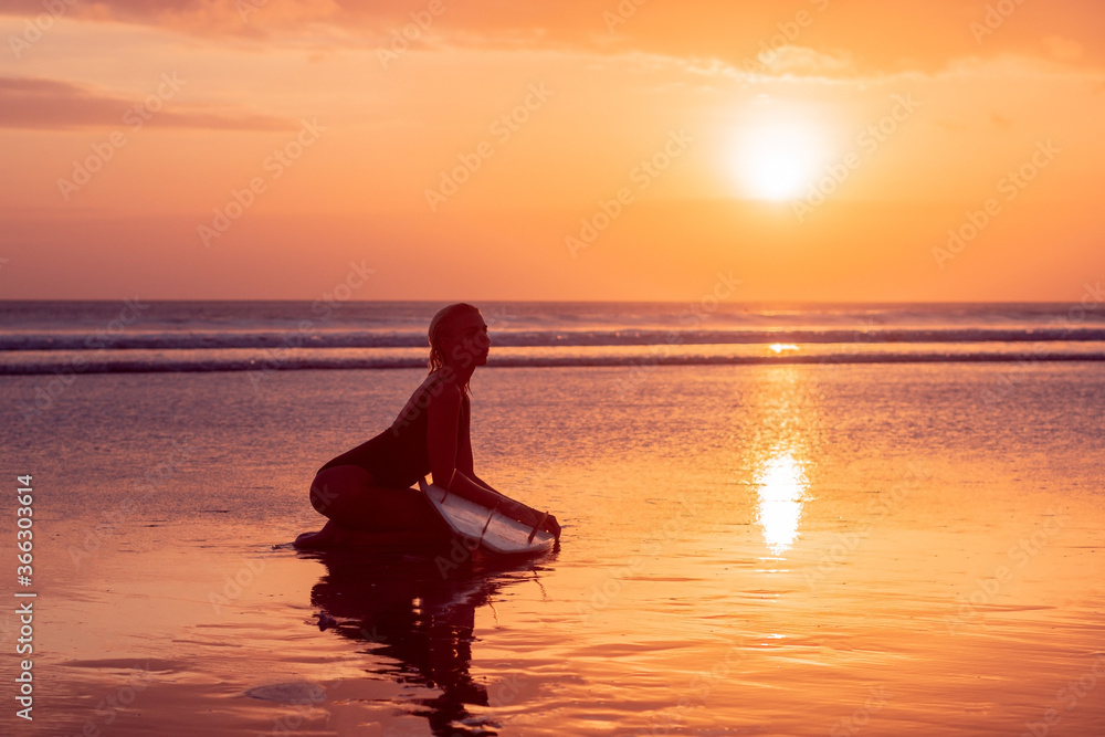 Portrait of surfer girl with beautiful body on the beach with surfboard at colourful sunset time