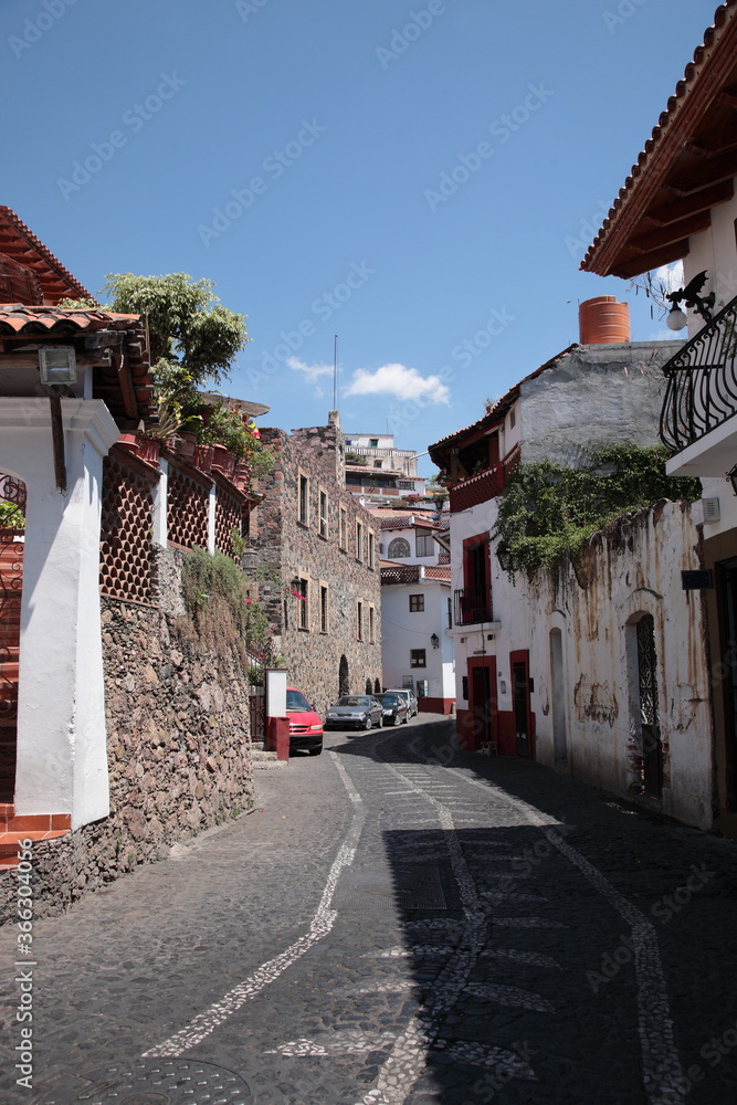 A typical view of narrow cobblestone streets with white and red houses with tile roofs  in Taxco, Mexico